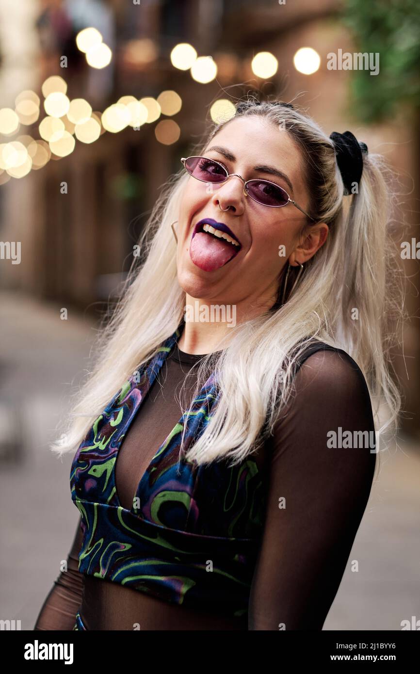 Alternative woman making a face sticking out her tongue while posing outdoors in the street. Stock Photo