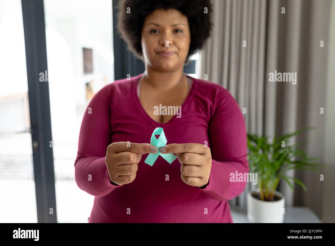 Portrait of african american mid adult woman showing prostate cancer awareness blue ribbon Stock Photo