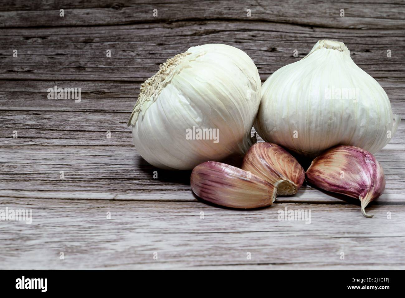 A closeup of fresh garlic cloves on a rough wooden table background ...