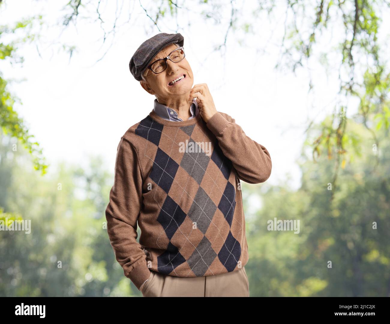 Elderly man itching his neck in a park with trees Stock Photo