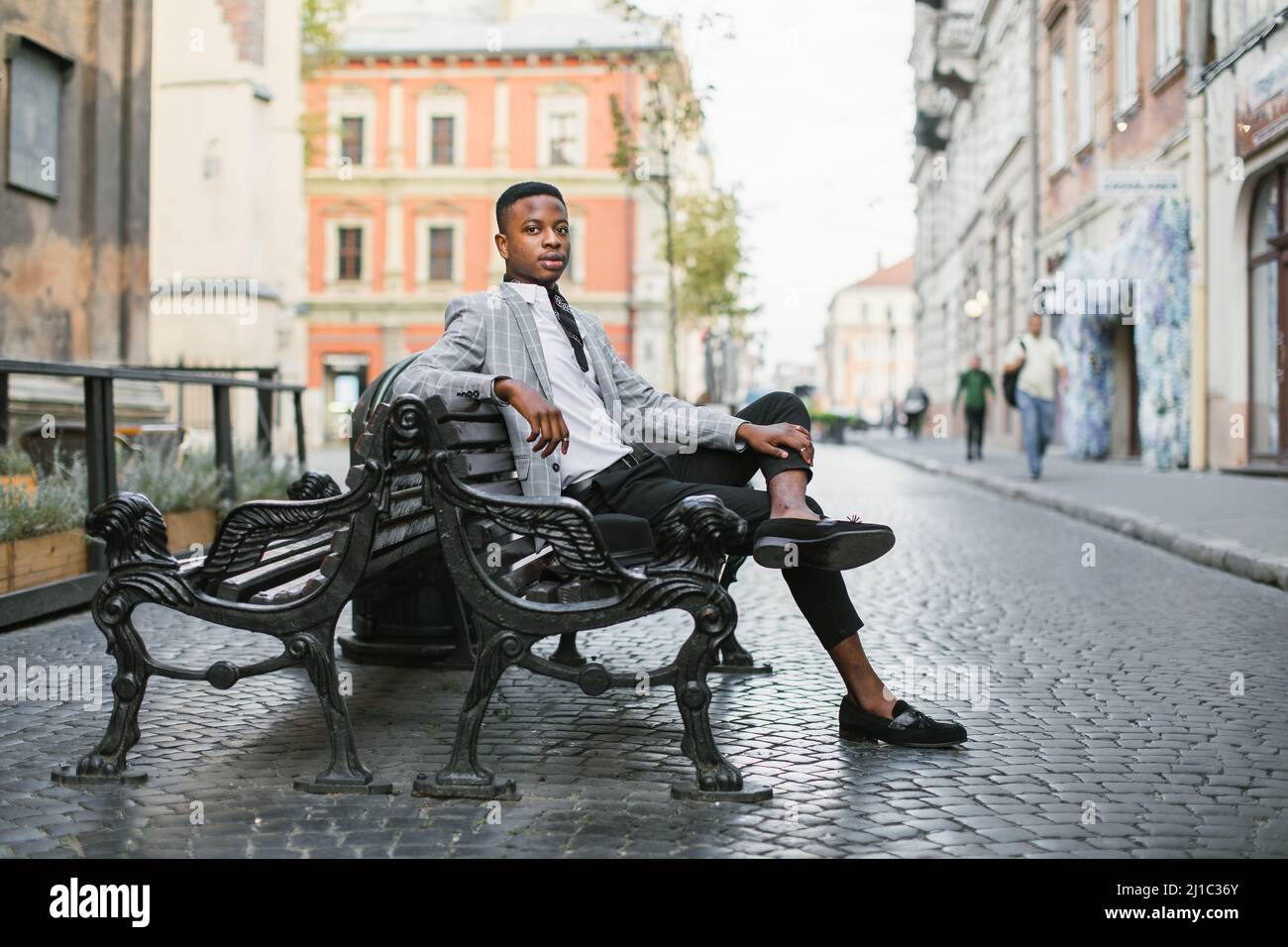 Confident african businessman in stylish suit sitting alone on bench ...