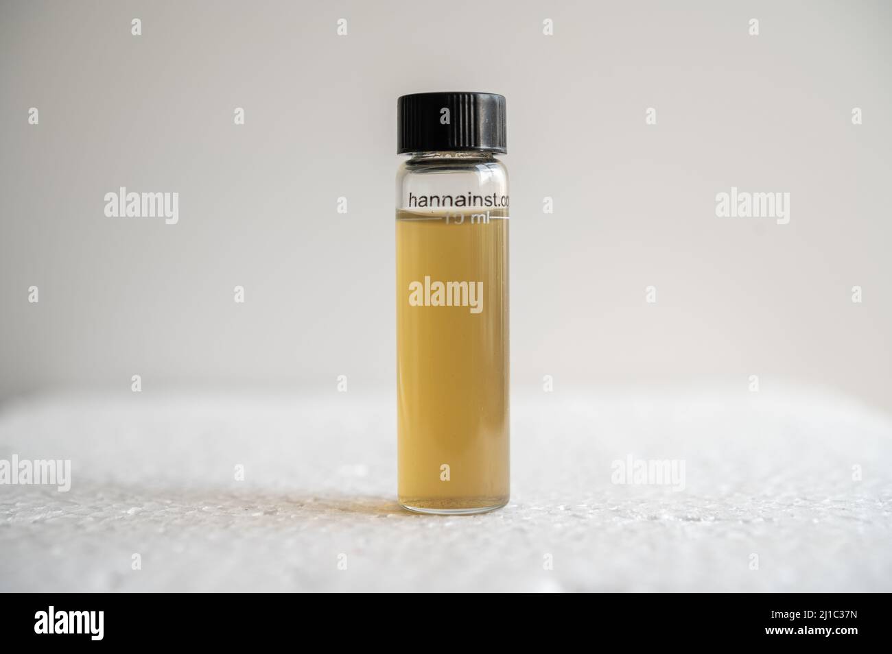 Brown and turbid unreacted sample of polluted stream water in a cuvette Stock Photo