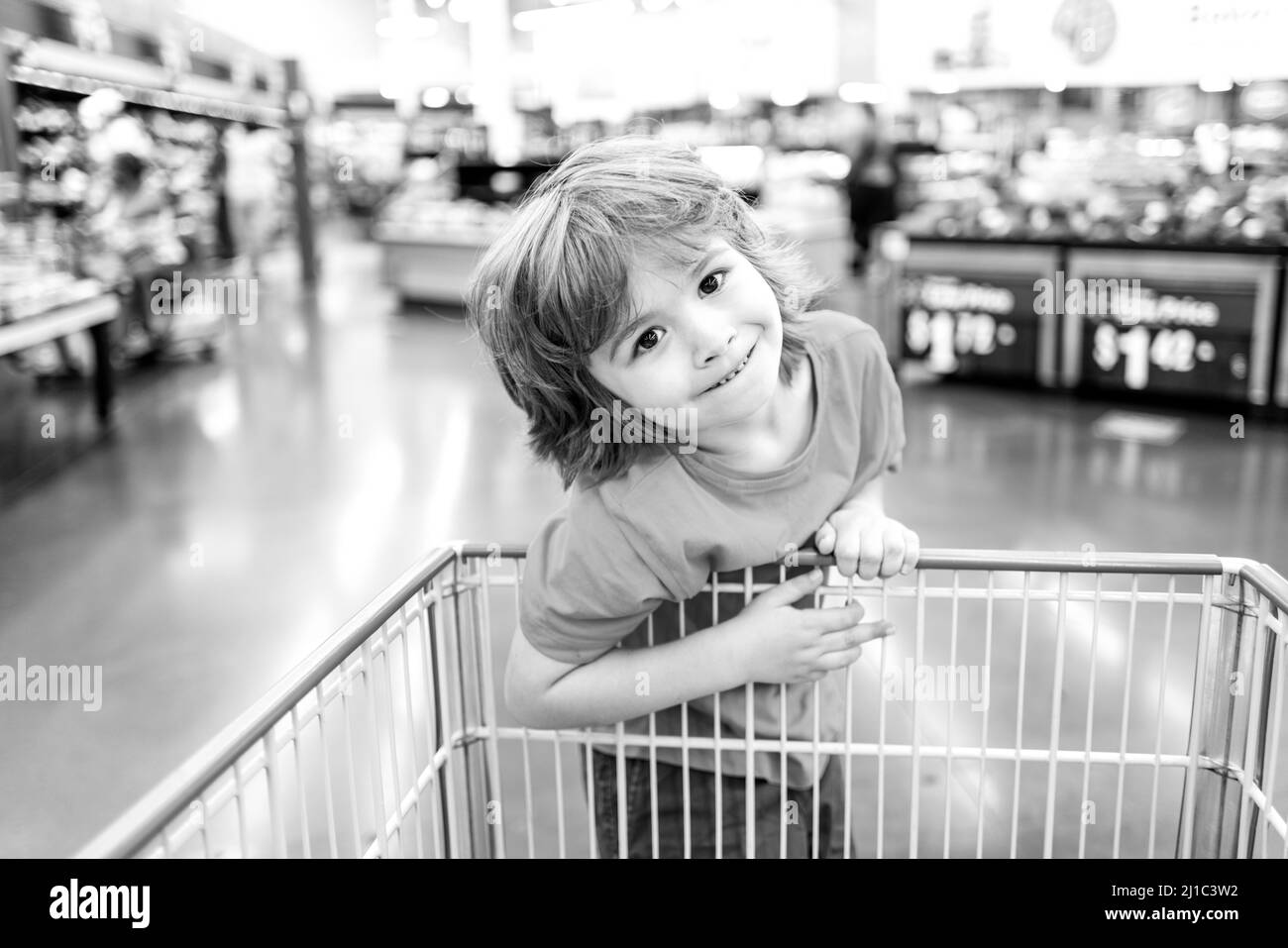 Funny customer boy child holdind trolley, shopping at supermarket, grocery store. Stock Photo