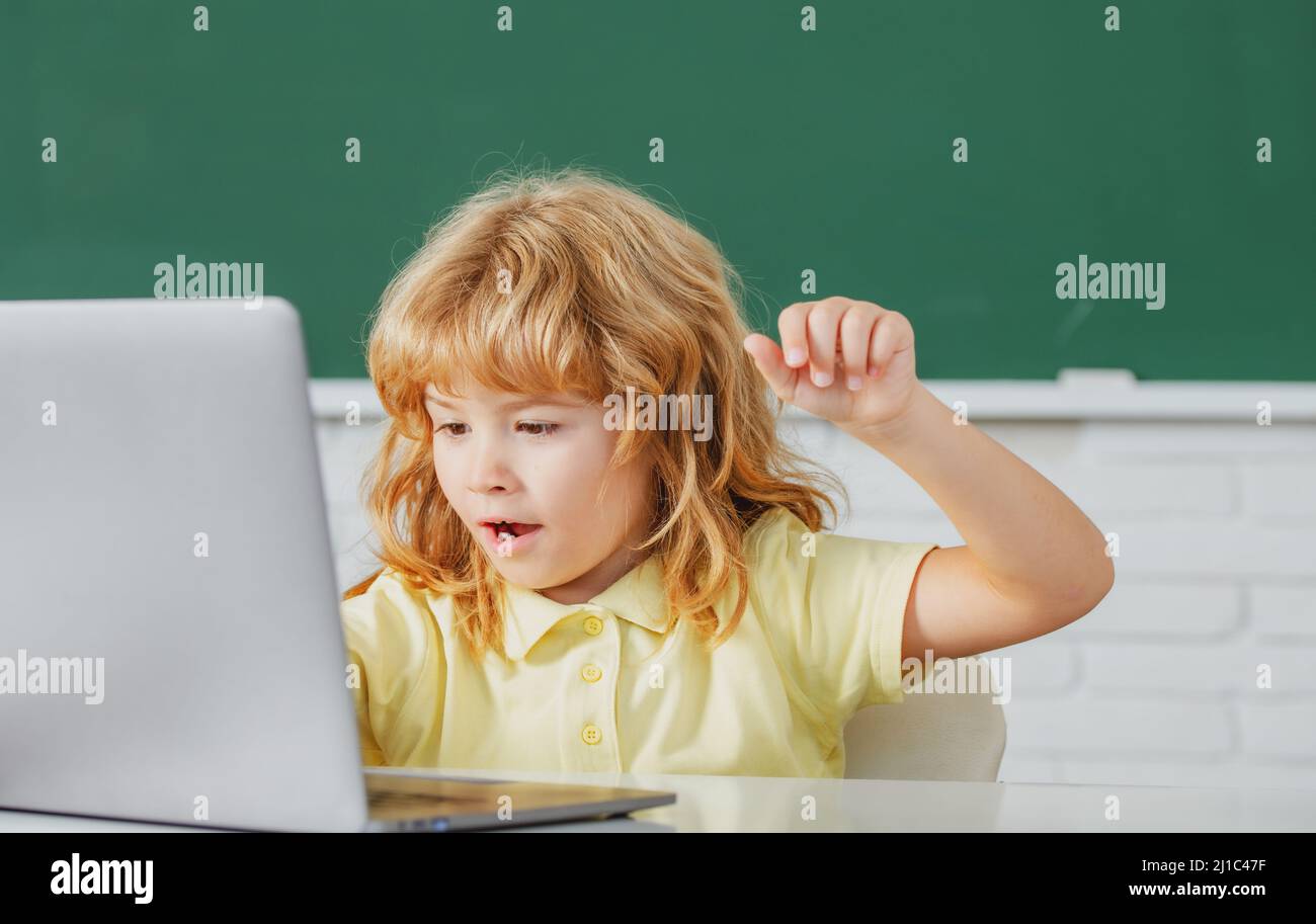 School child using digital pc laptop in class. Portrait of funny pupil of primary school study programming. Online learning technology, virtual Stock Photo