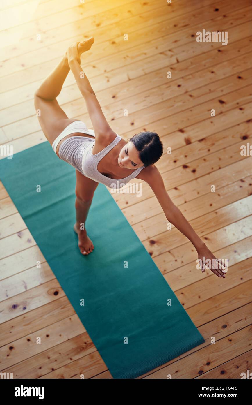 Perfection the balance between mind and body. High angle shot of a young woman doing yoga indoors. Stock Photo