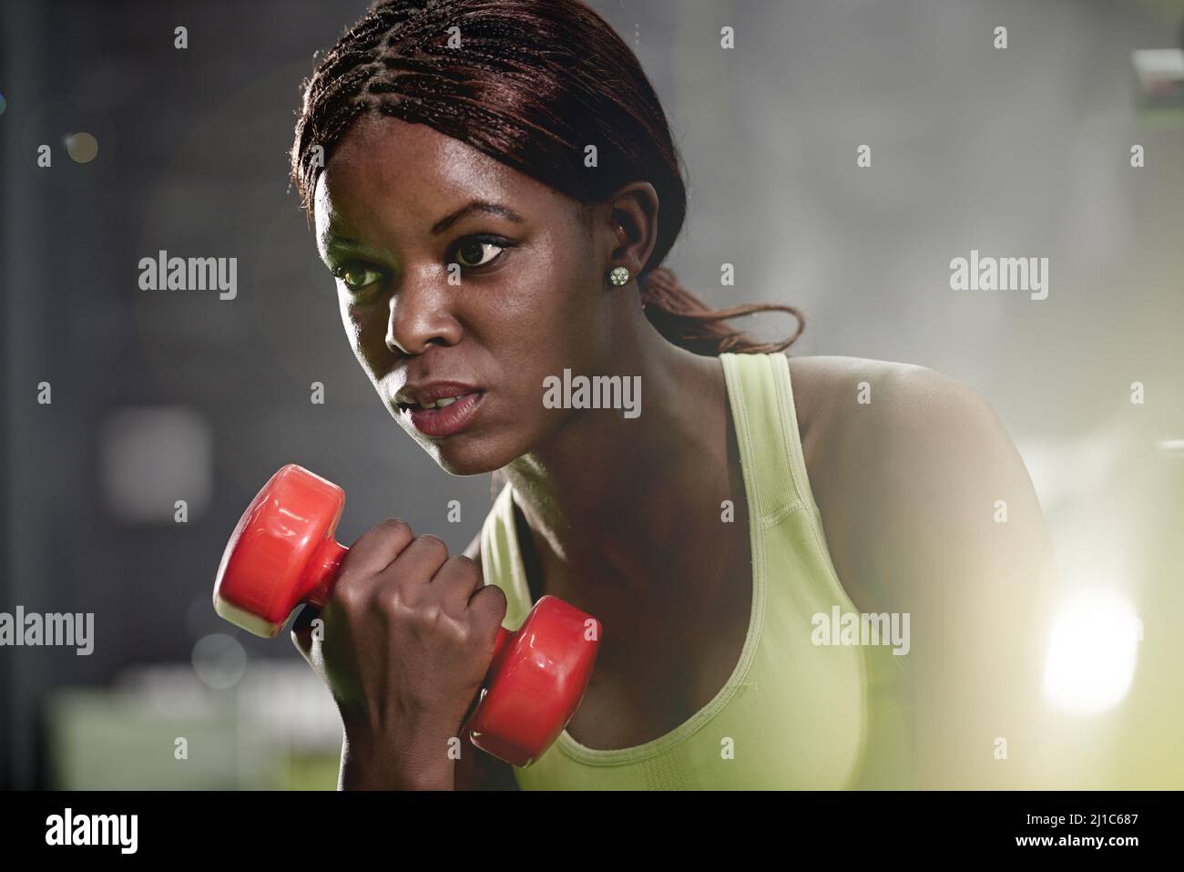 Make every lift count. Shot of a young woman lifting weights at the gym