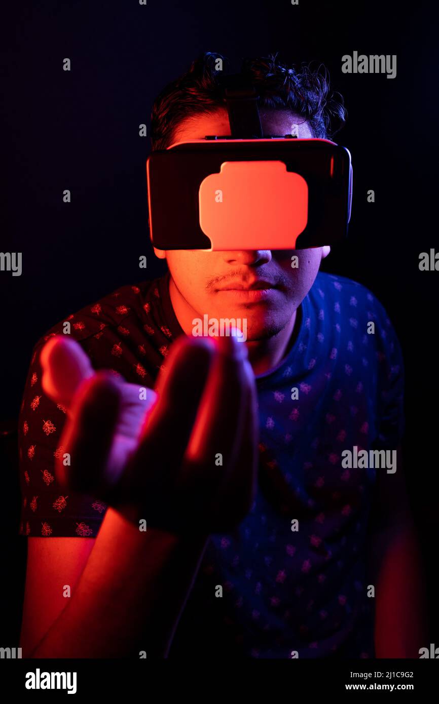 Young latin man using Virtual Reality VR Headset 3D Glasses. Dark backdrop. Low key. Stock Photo