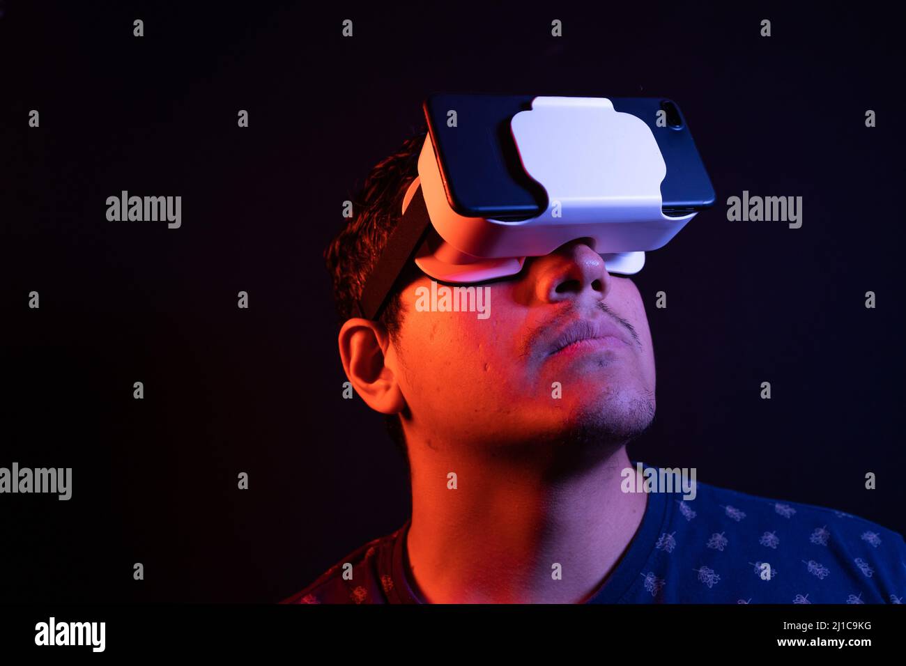 Young latin man using Virtual Reality VR Headset 3D Glasses. Studio dark backdrop. Low key.  Stock Photo