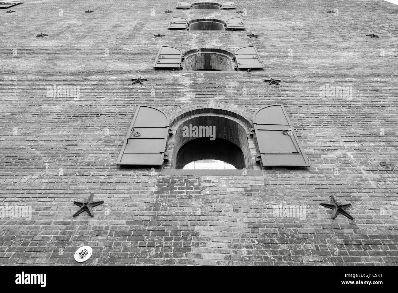 A grayscale low angle shot of an old building with open windows Stock ...