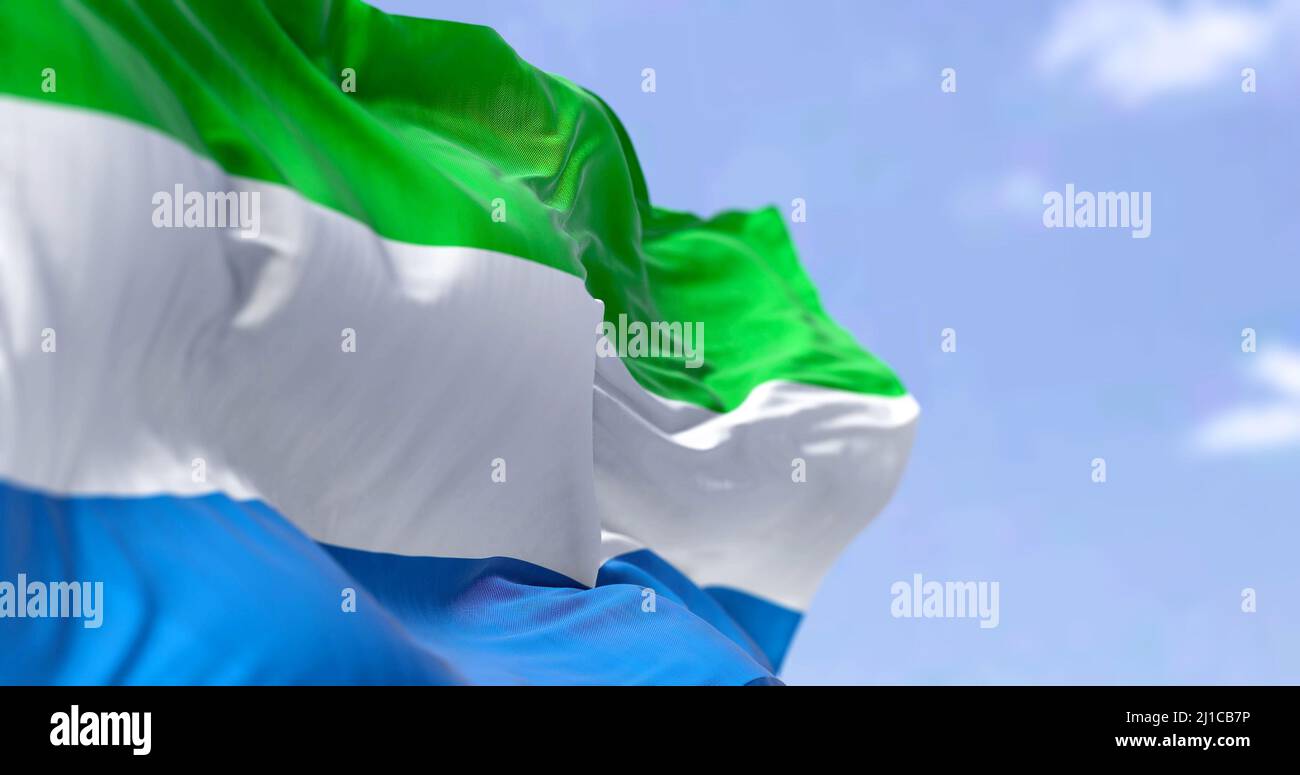 Detail of the national flag of Sierra Leone waving in the wind on a clear day. Sierra Leone is a country on the southwest coast of West Africa. Select Stock Photo
