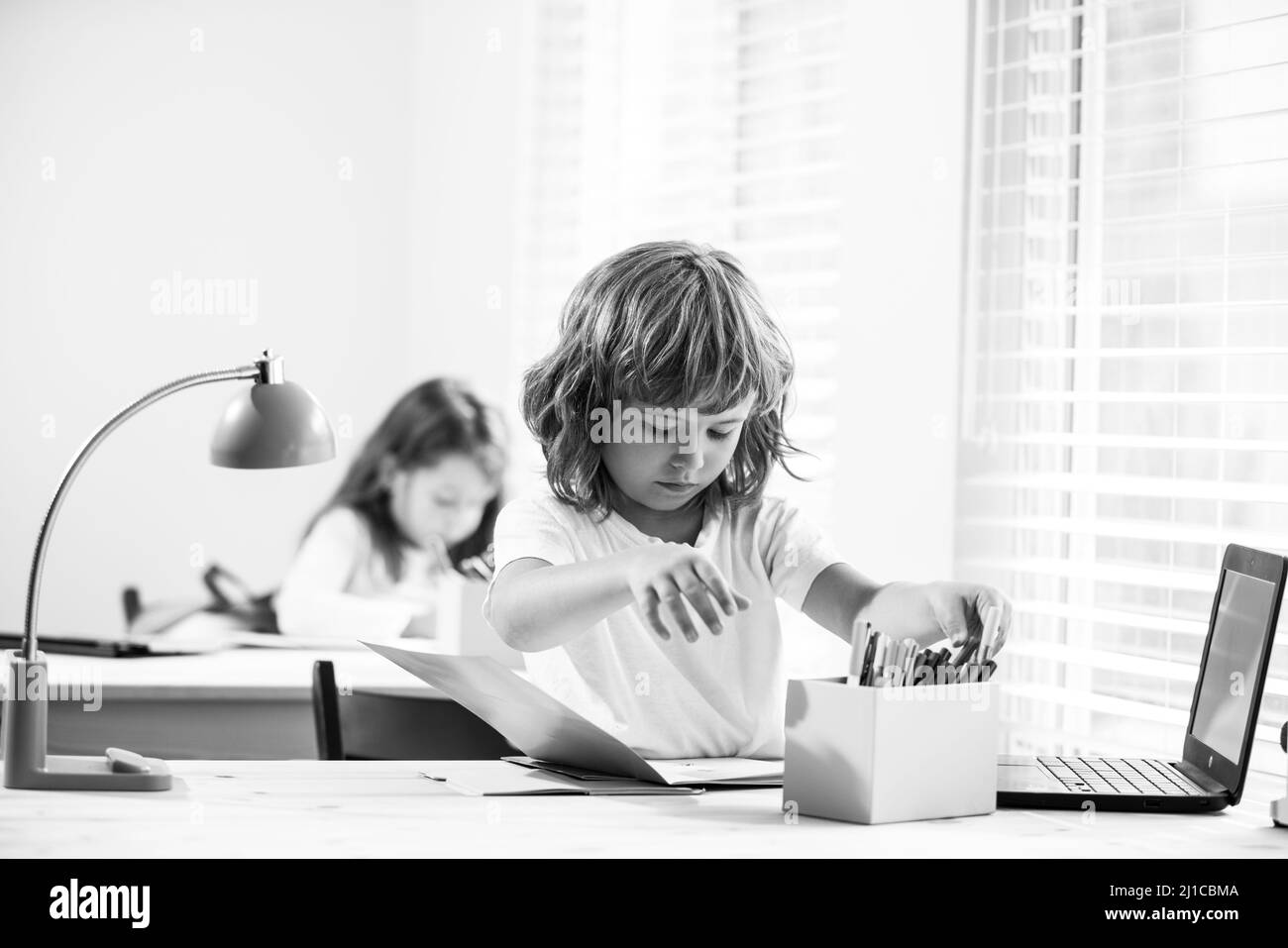 School boy sitting at the table, writing homework or preparing for the exam. Child ready to study. Little studen learning. Stock Photo