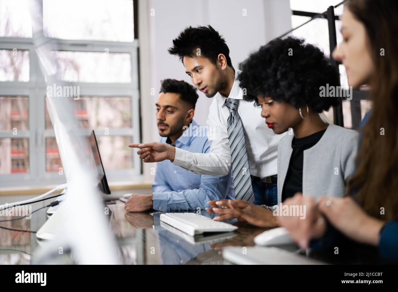 Group Of Happy Business People Using Laptop Discussing At Workplace In Office Stock Photo