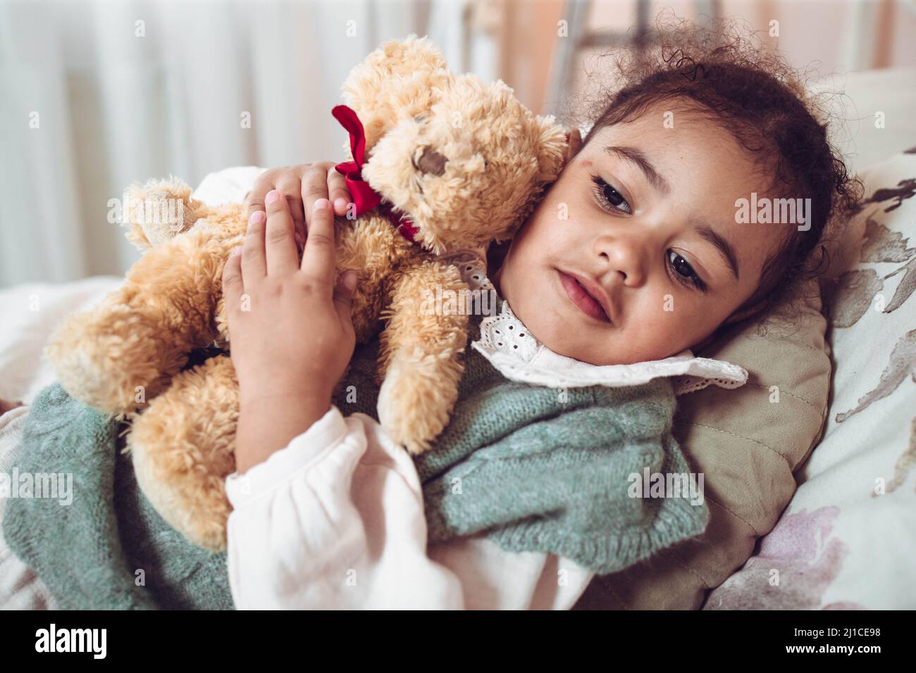 Adorable multiethnic little girl hugging her bear Stock Photo