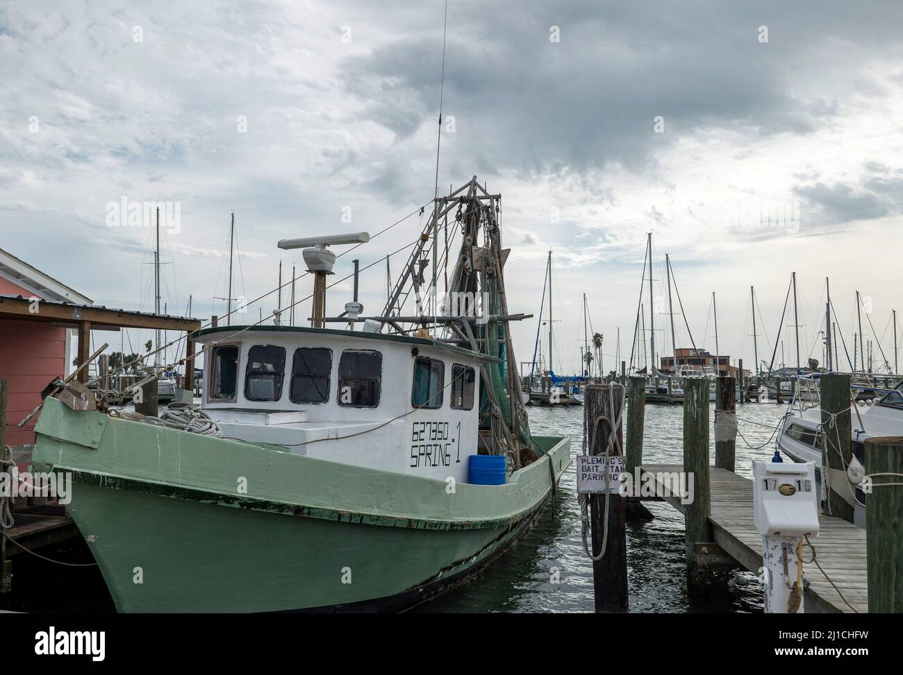 ROCKPORT, TX - 3 FEB 2020: Green and white shrimp boat tied by rope to the wooden dock in a marina. Stock Photo
