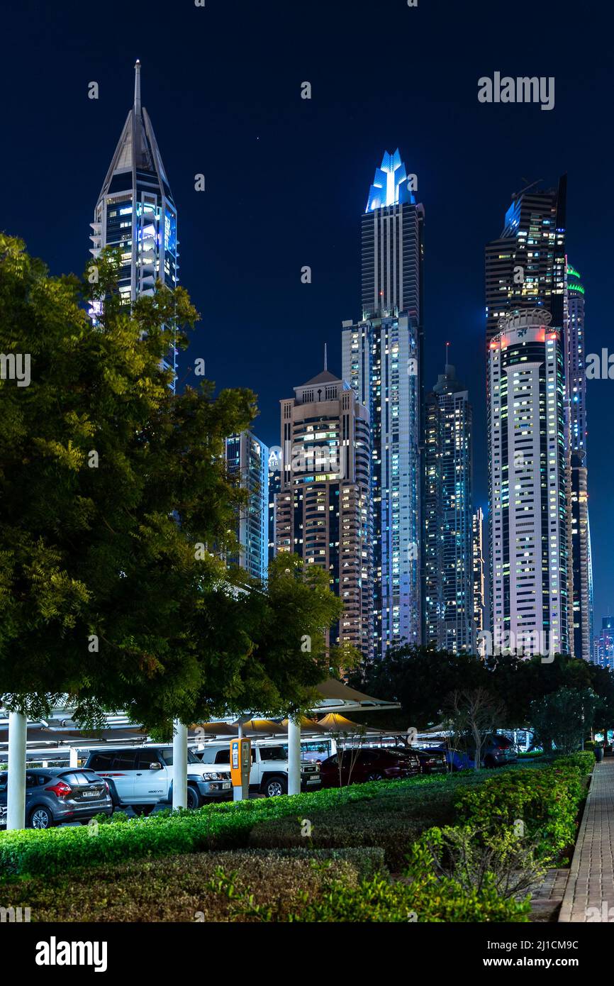 Dubai, UAE - Dec 05 2021: Vertical view of Dubai Marina skyscrapers with parking cars in front az night; Dubai cityscape wallpaper Stock Photo