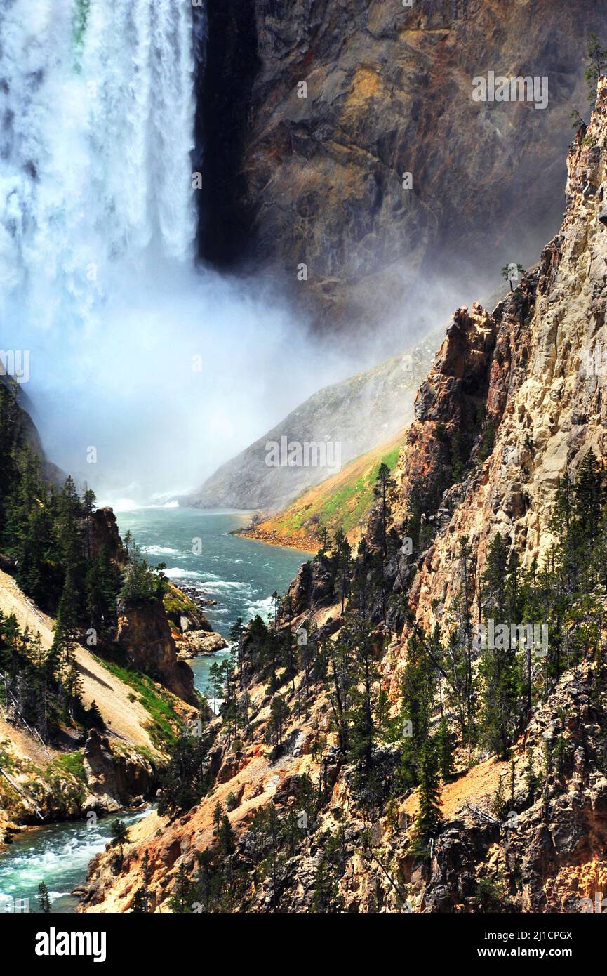 Bottom of Lower Falls in Yellowstone National Park has thunderous spray and crashing water.  Yellowstone River curves and twists its way through the s Stock Photo