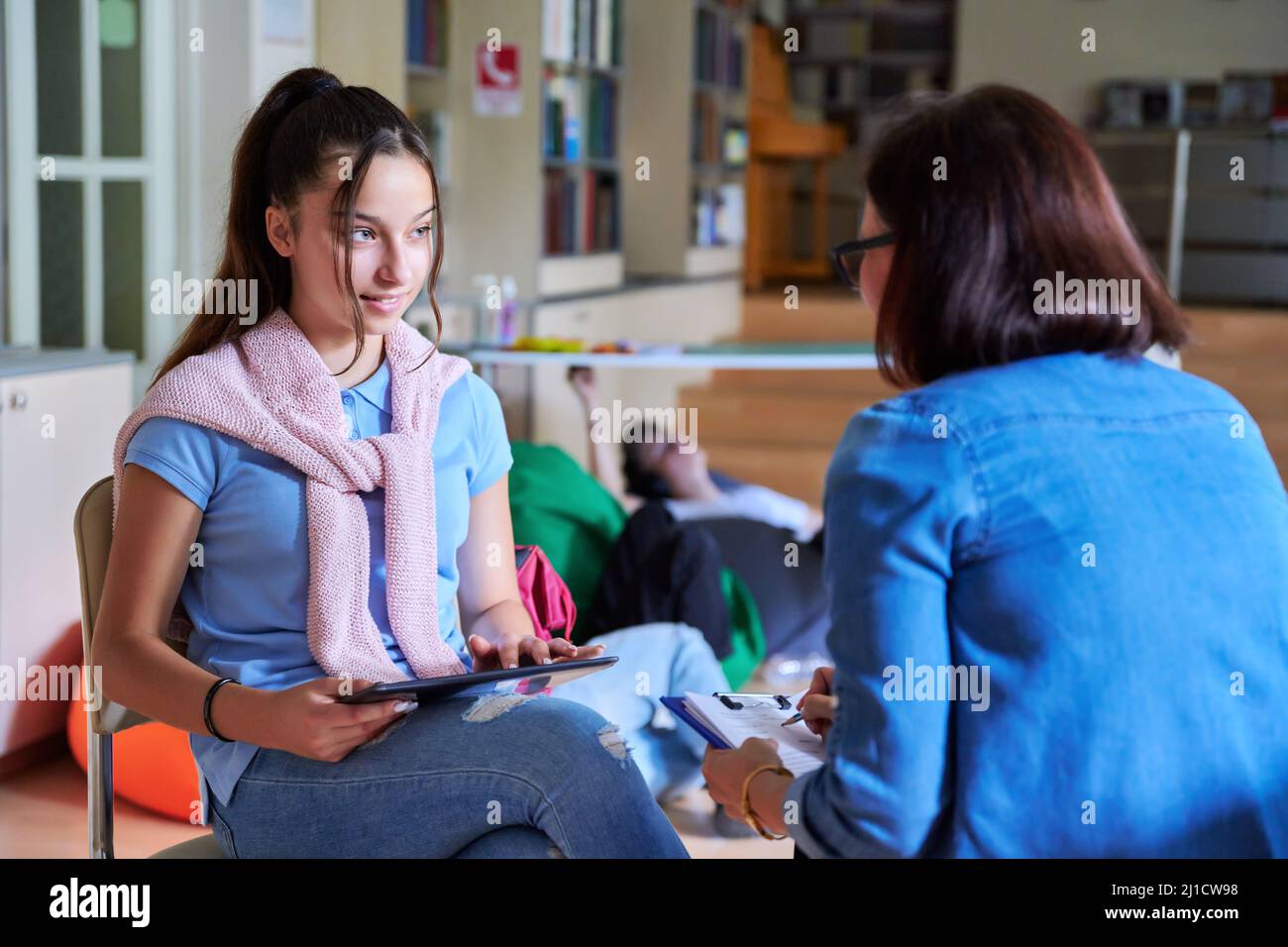 Woman school psychologist teacher talking and helping student, girl teenager Stock Photo