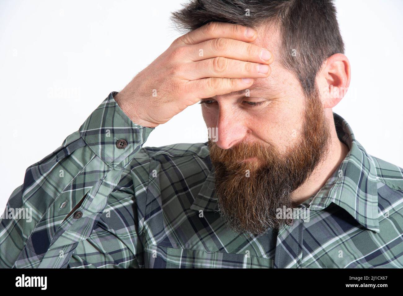 Upset man standing with his hand holding his forehead Stock Photo