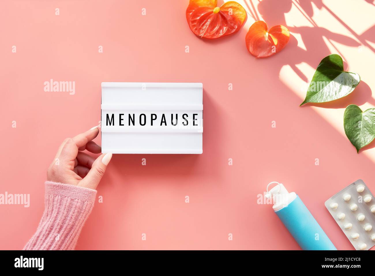Text Menopause on light box in hand. HRT Replacement hormone therapy