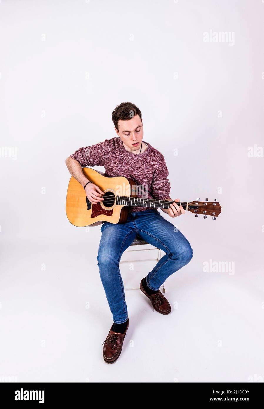 teenage guitar player sits on a chair and plays guitar Stock Photo - Alamy