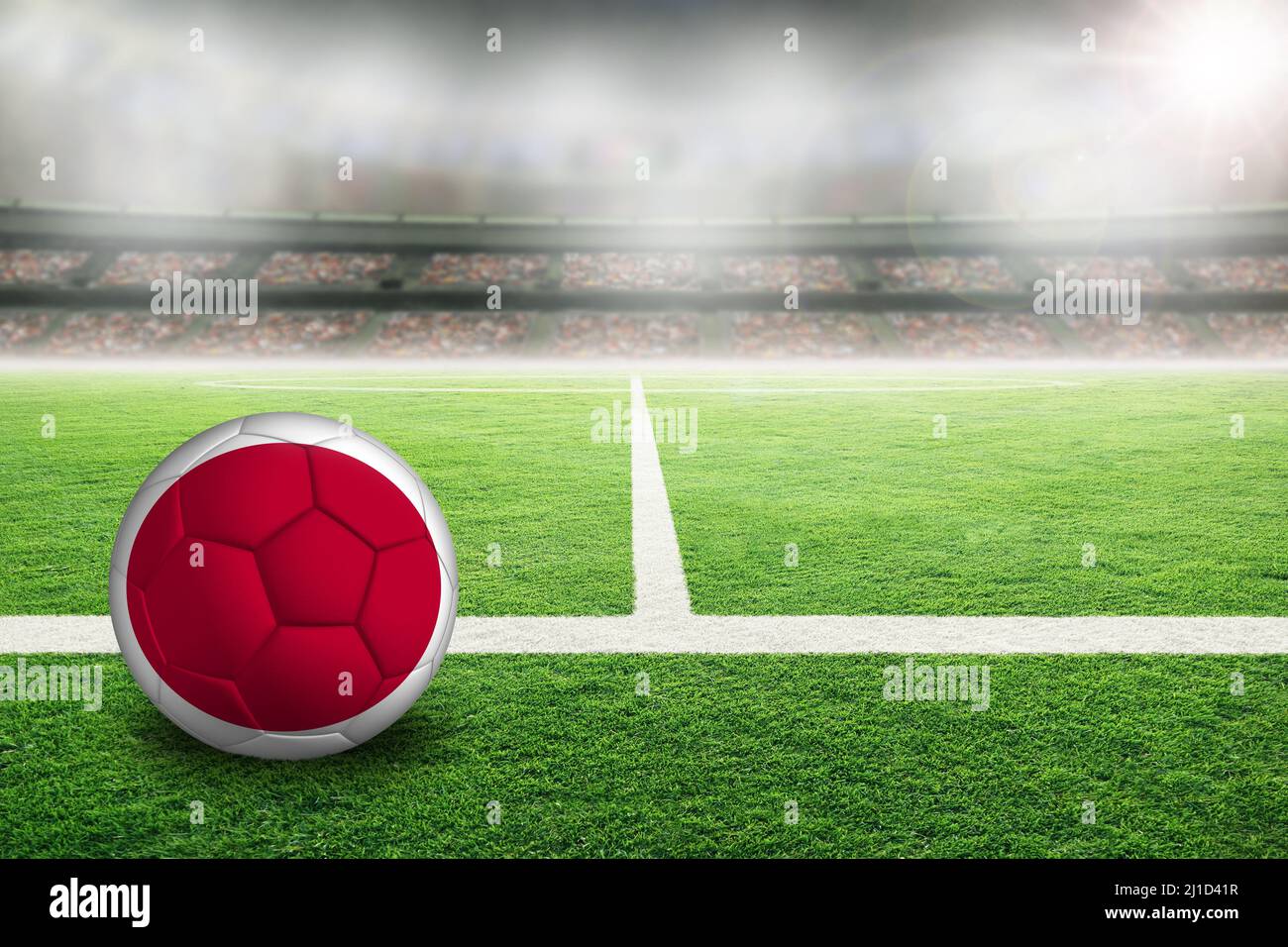 Football in brightly lit outdoor stadium with painted flag of Japan. Focus on foreground and soccer ball with shallow depth of field on background and Stock Photo