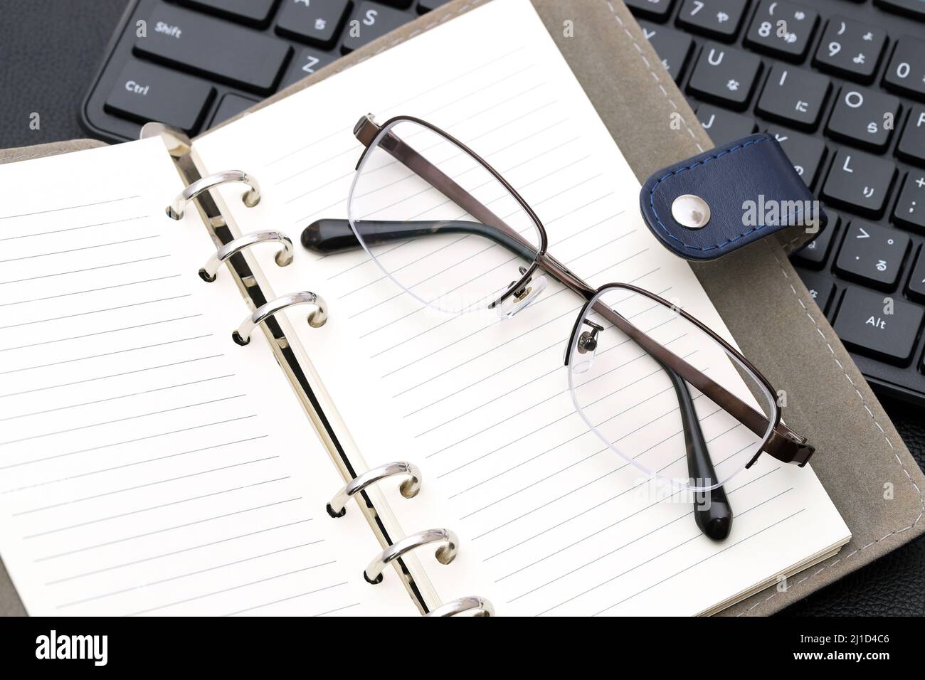 Eyesight glasses with note book, computer keyboard. Alphabetics and Japanese hiragana typing keyboard. Stock Photo