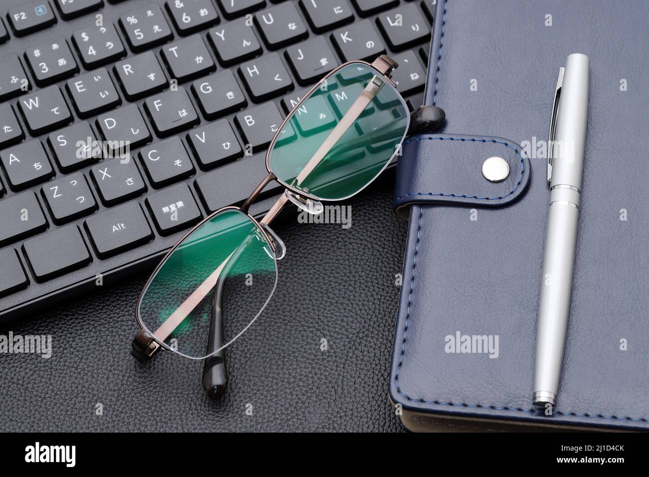 Eyesight glasses with note book, computer keyboard. Alphabetics and Japanese hiragana typing keyboard. Stock Photo