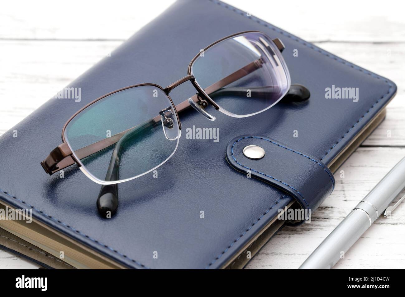 Stylish eyesight glasses with note book on wooden table Stock Photo
