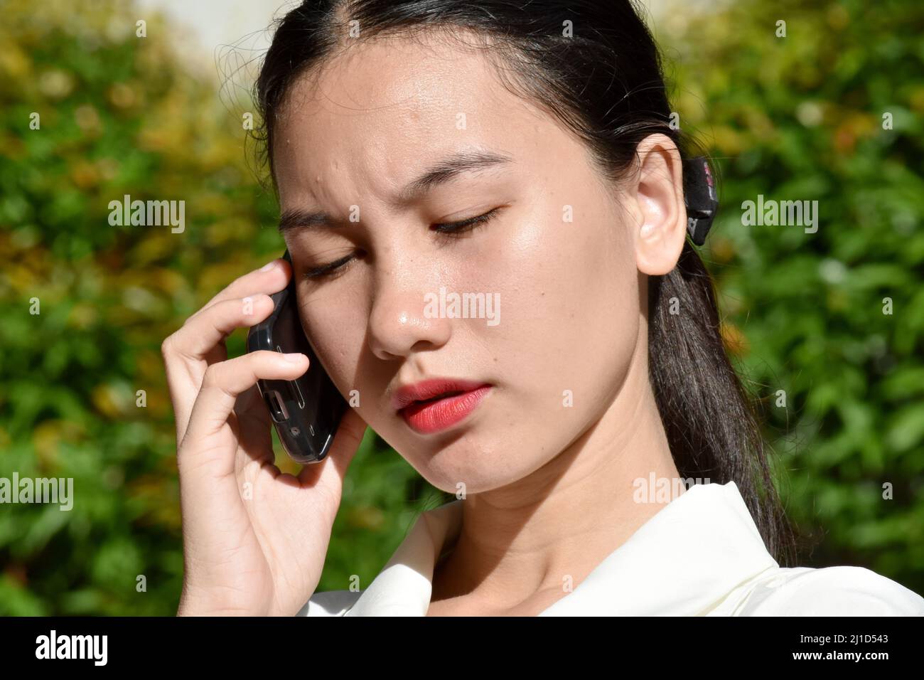Unemotional Pretty Filipina Person With Cell Phone Stock Photo