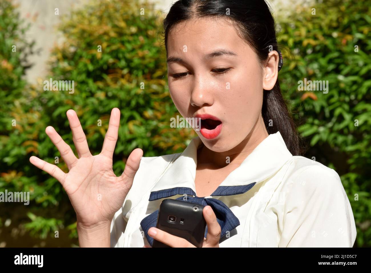 Shocked Filipina Adult Female With Mobile Phone Stock Photo
