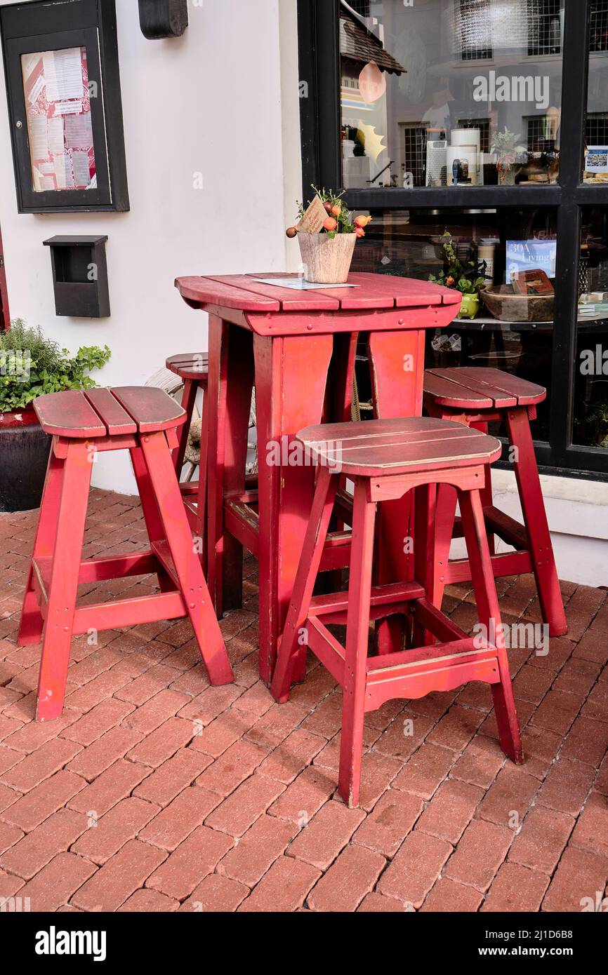 Small outdoor red high top table and set of stools in front of a small restaurant in Rosemary Beach Florida, USA. Stock Photo