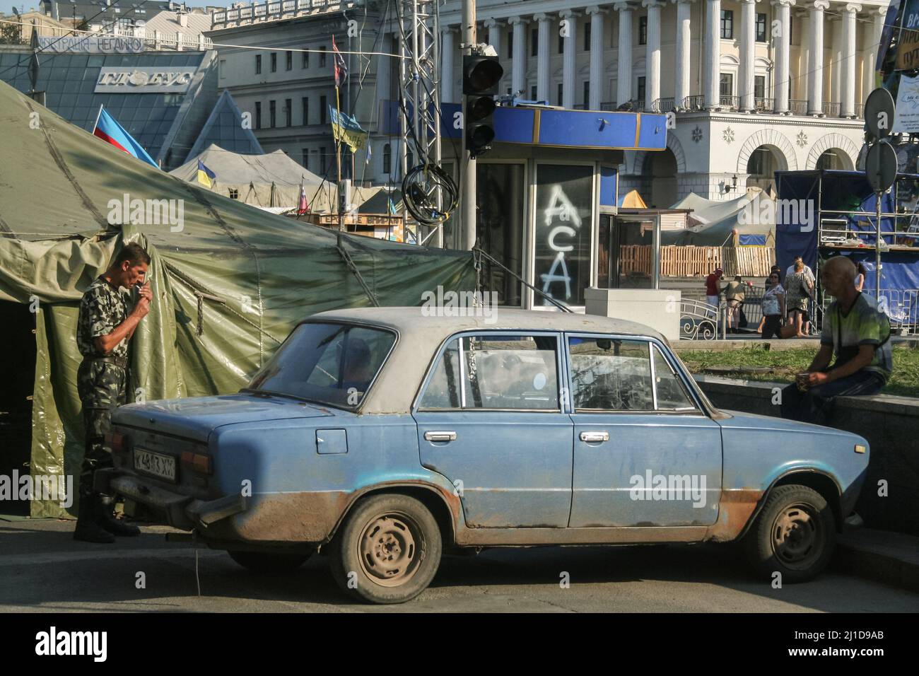 Picture of barricades and tents hosting protesters after the 2014 Maidan revolution, on Maidan square in Kyiv, Ukraine with men standing in front of a Stock Photo