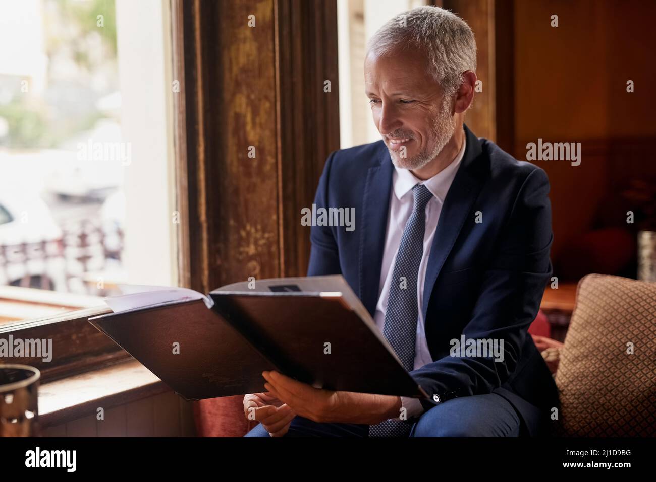 Whats on the menu for today. Shot of a well-dressed mature man reading a menu in a cafe after work. Stock Photo