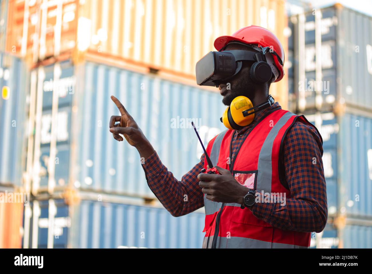African-American male engineers wearing VR Headset look container cargo ship. Stock Photo