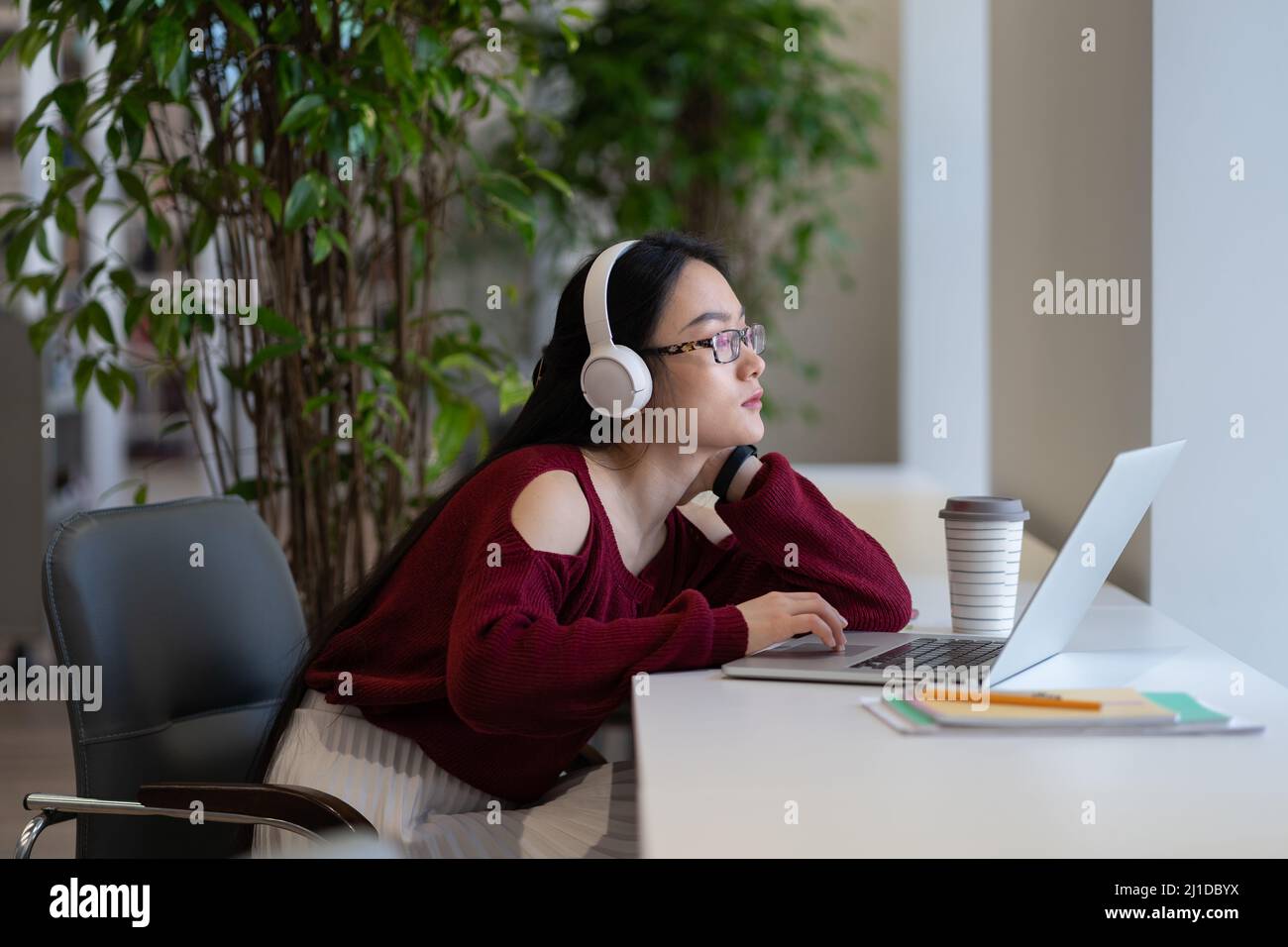 Asian female freelancer in headphones working laptop screen in ...