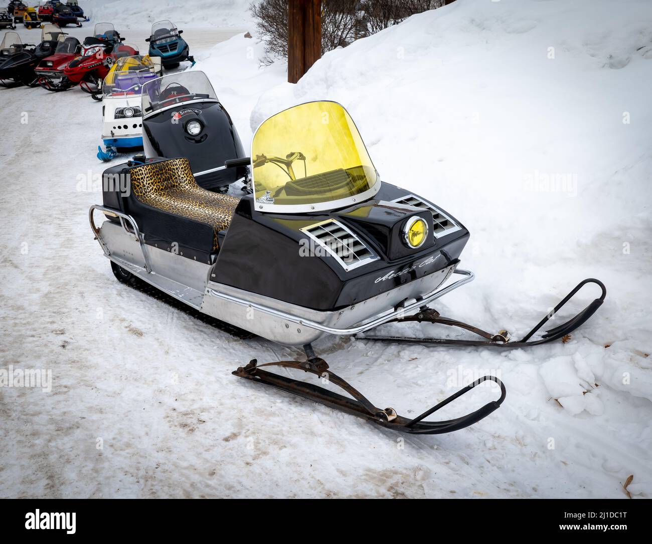 NISSWA, MN - 5 JAN 2022: Old Arctic Cat Panther snowmobile sits on the snow of a parking lot with other sleds. A black 1970s vintage sled with tinted Stock Photo