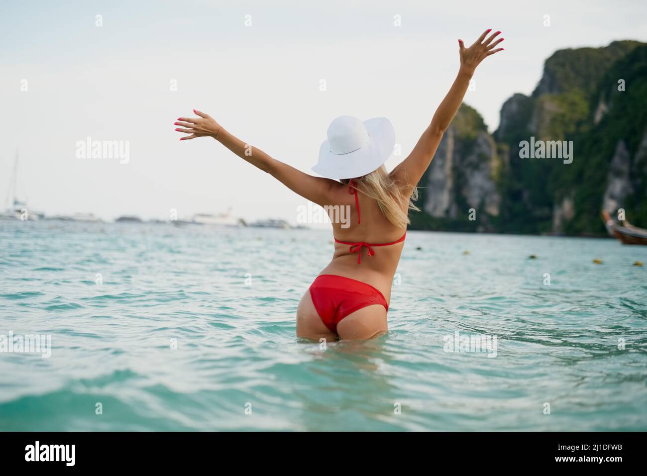 Got that summer feeling. Rearview shot of a young woman posing with her bikini in the water. Stock Photo