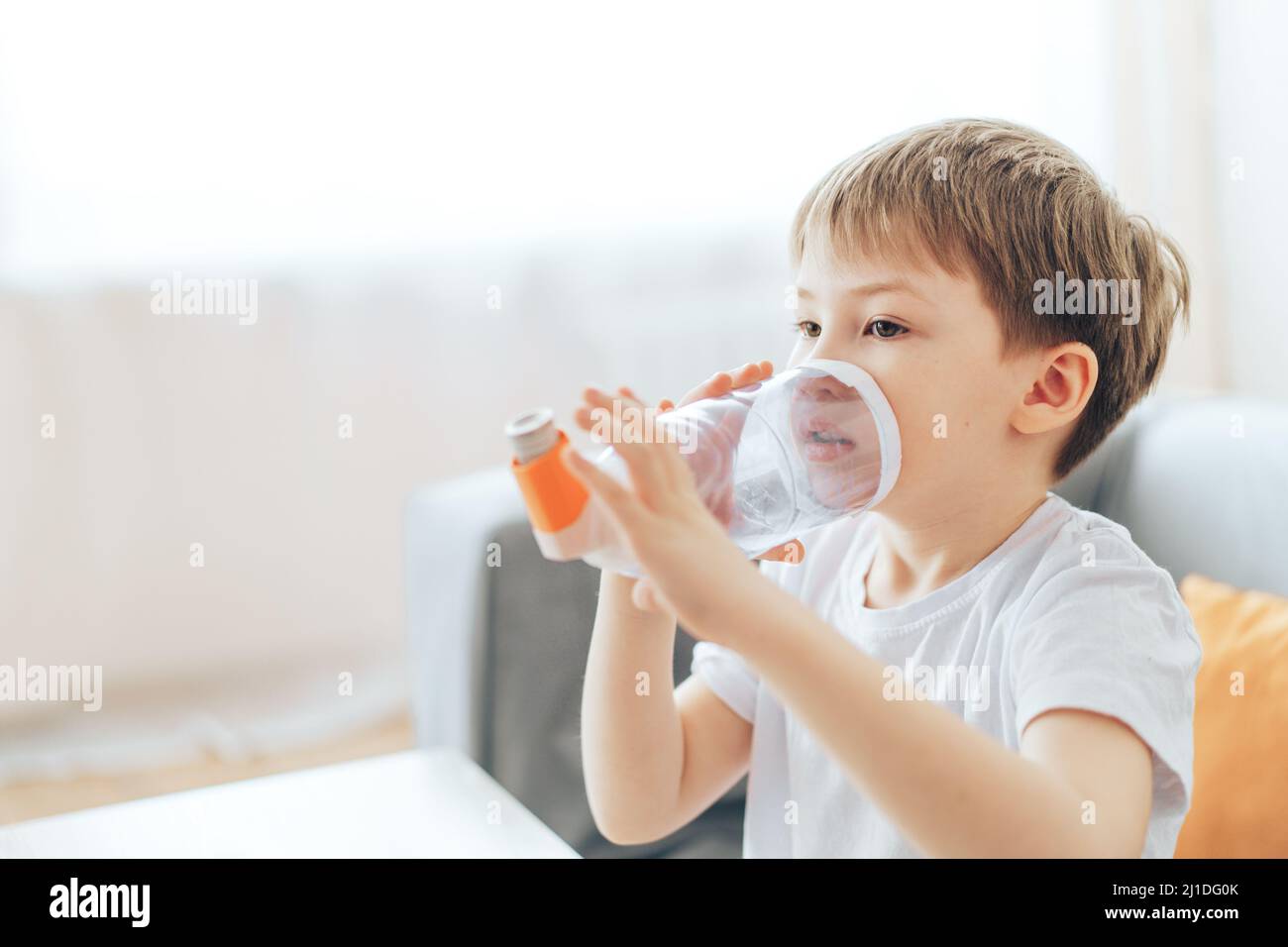 Little boy inhales asthma medicine through homemade spacer Stock Photo