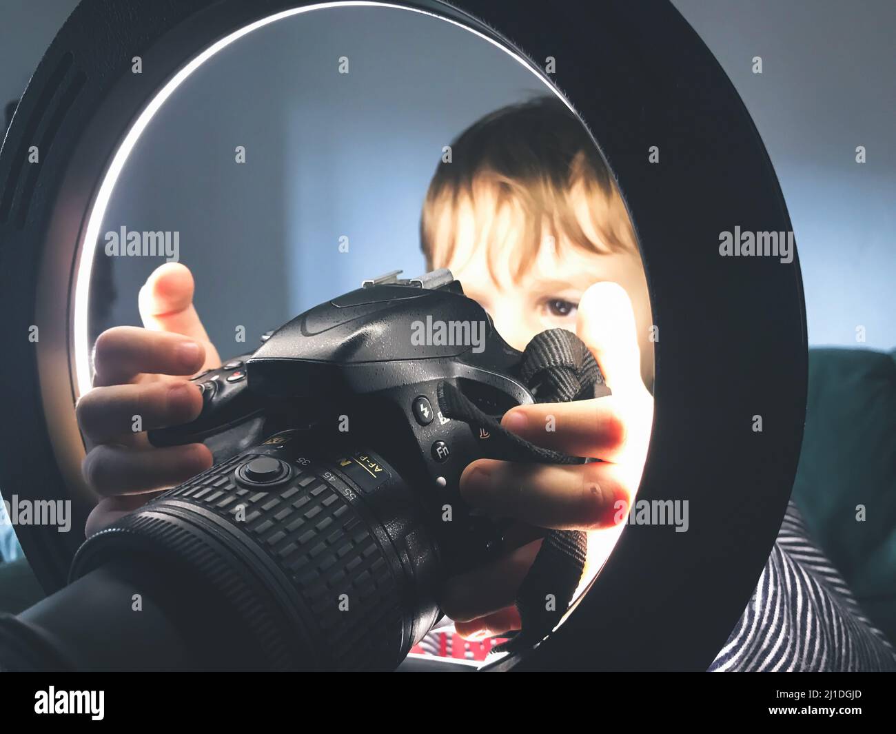 Young child photographer looking through camera and light rings, 2 years old child in studio Stock Photo