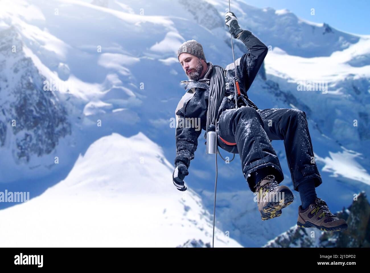 Just a little further.... Shot of a mountaineer hanging from a rope on a rockface. Stock Photo