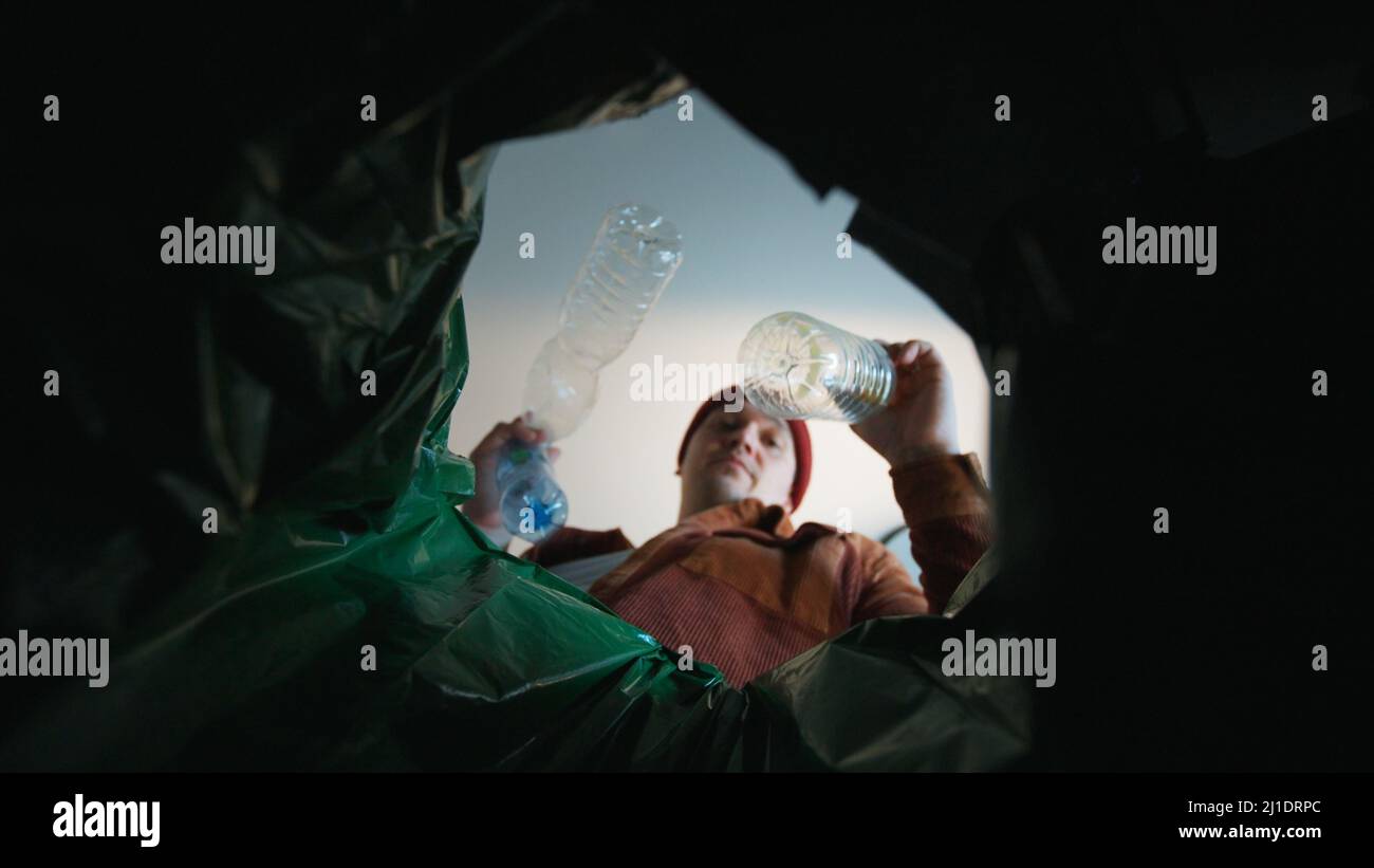 Man throwing a plastic bottle into a trash bin. Bottom view from the ...