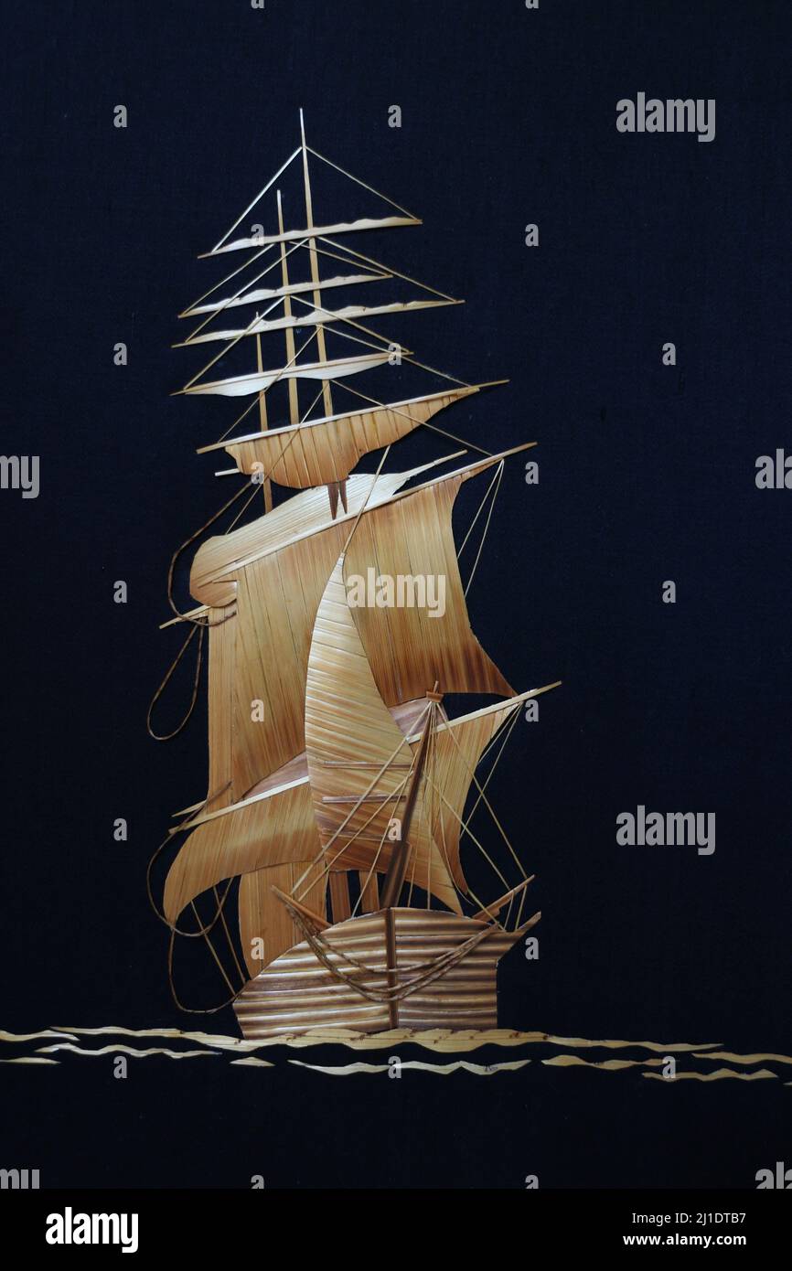 sailing ship front view in the sea on a dark background, carved panel straw Stock Photo