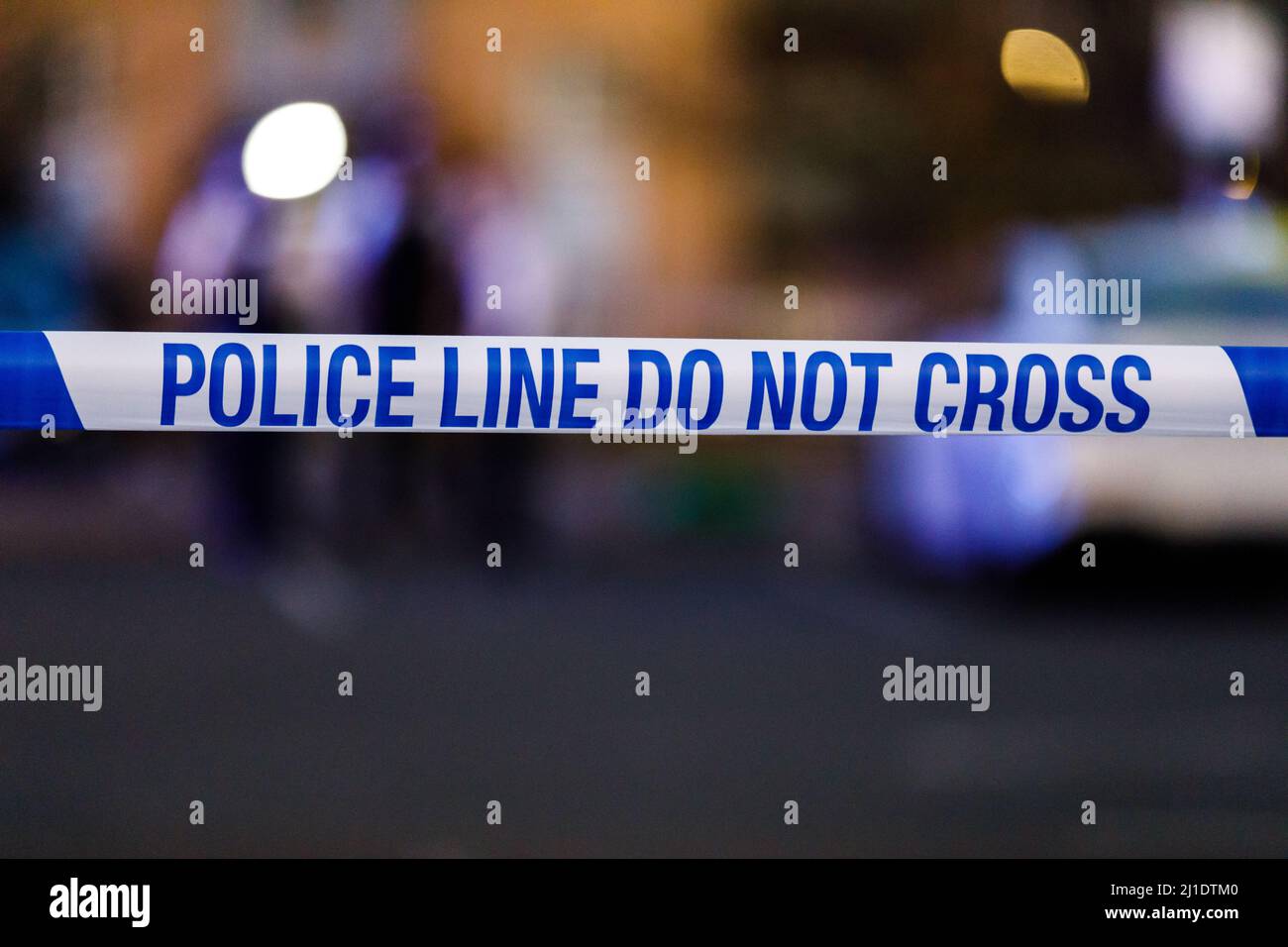 Blue and White POLICE LINE DO NOT CROSS cordon tape at the scene of a crime in the UK Stock Photo