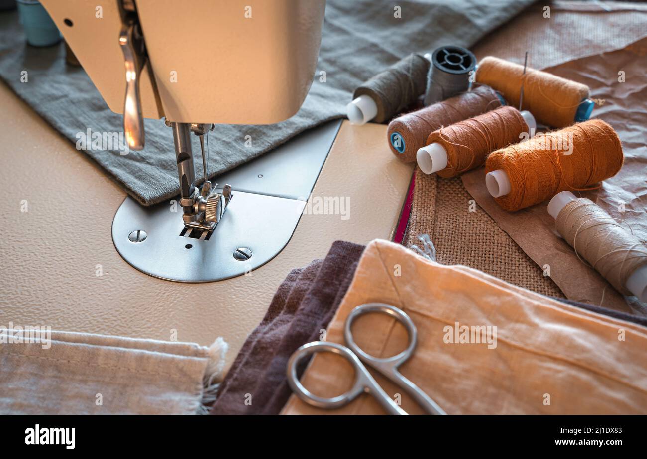 Sewing machine, thread, scissors and fabric close-up. Design workplace. Stock Photo