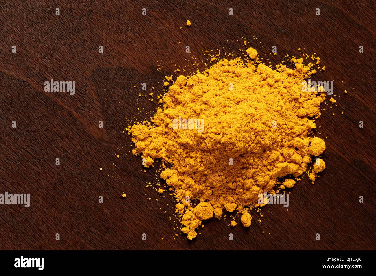 Heap of curry powder on dark wood. Top view. Stock Photo