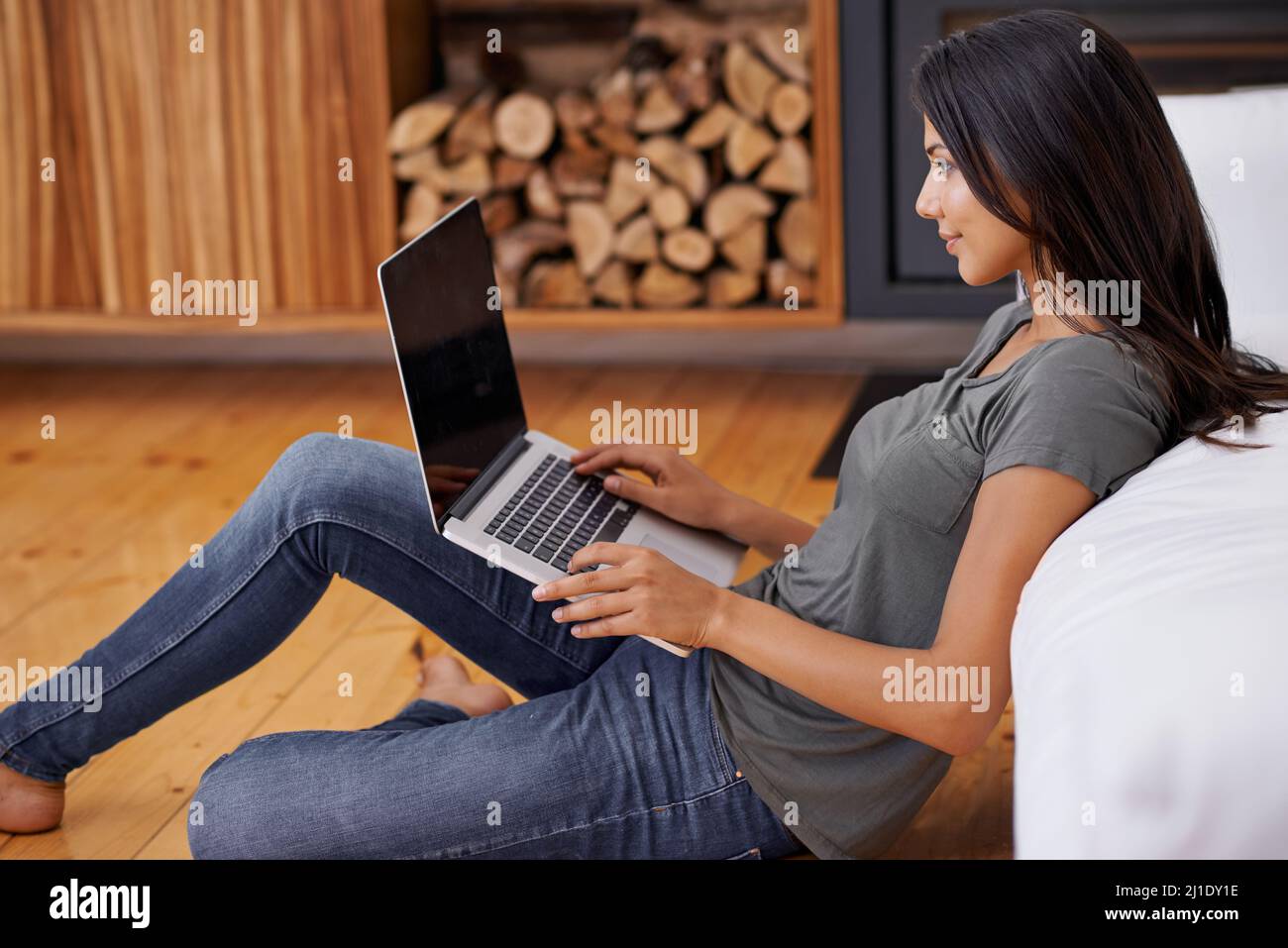 This is how I chill. Shot of a young woman using a laptop while relaxing at home. Stock Photo