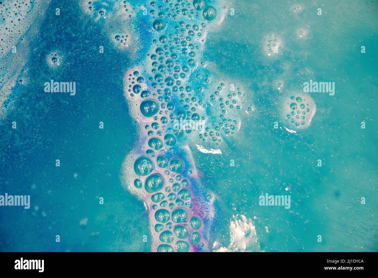 Bright colorful bath foam from the water bomb. Blue and pink bubbles and waves and spray Stock Photo