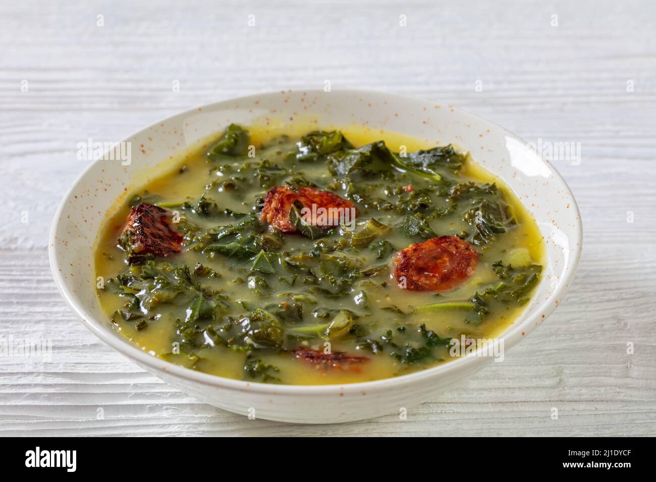 Caldo Verde, Portuguese potato and kale green soup with Chorizo Sausage in white bowl Stock Photo