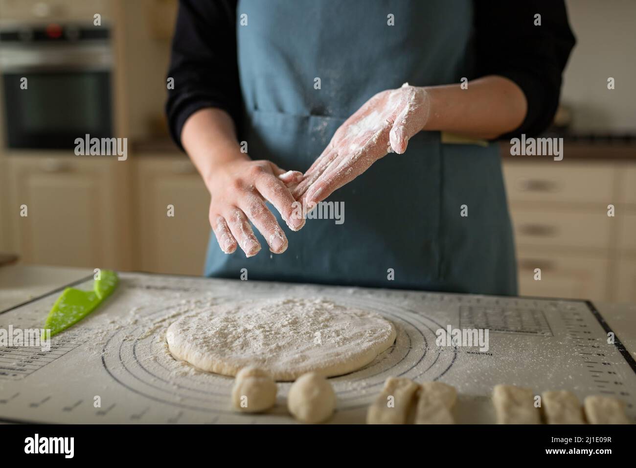 Hands in flour at the cook in a blue apron in a home bakery Stock Photo