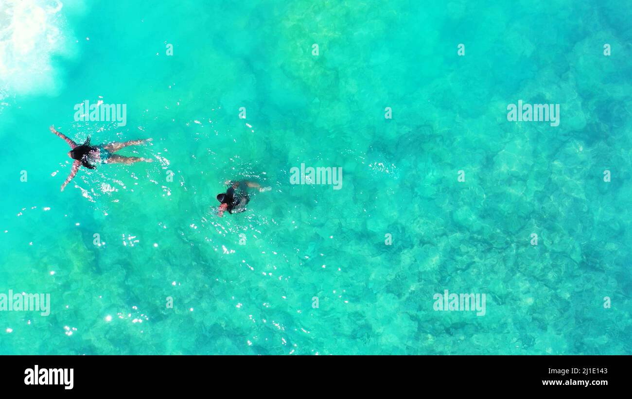 An aerial top view of two girls swimming in the ocean in Gili Meno
